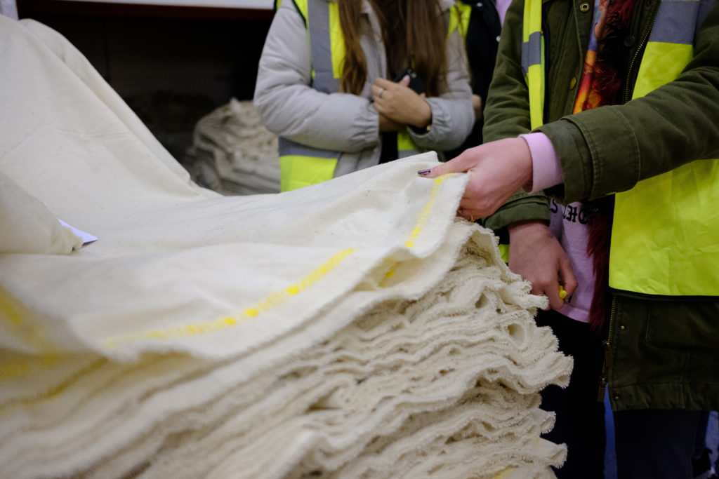 Students handle plain unfinished fabric at AW Hainsworth