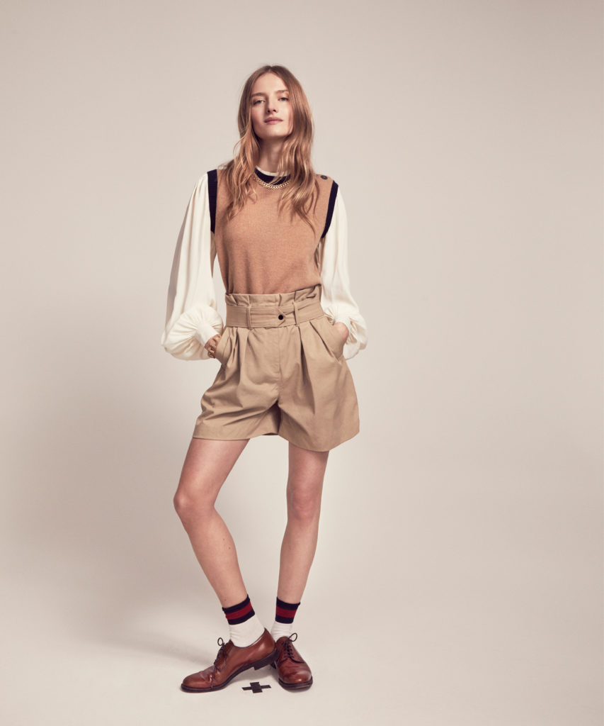 Model wears camel and navy jumper with beige shorts, brown brogues and ankle-length socks.