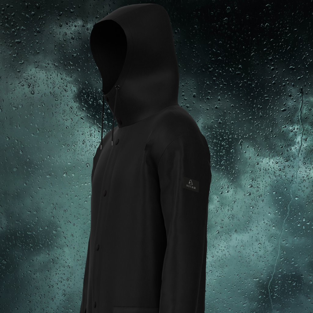 A black hooded raincoat with four buttons down the front against the backdrop of dark clouds and raindrops.