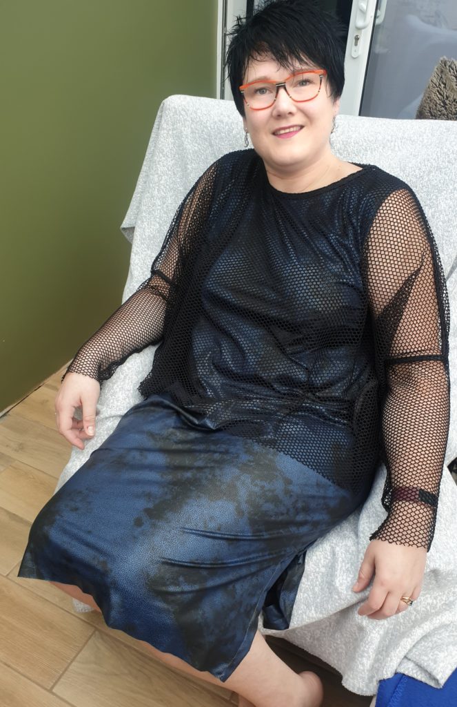 Kat Bent, founder of Seated Sewing, wearing a dark blue layered dress with black mesh sleeves