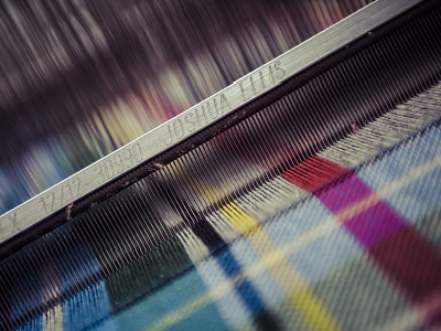 A close-up of a loom with 'Joshua Ellis' engraved on the metal