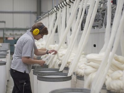 A skilled worker wearing headphones checks fibres before they are fully spun at Laxtons