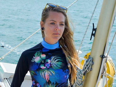 A model stands on a boat at sea wearing a high-necked watersports top in floral print