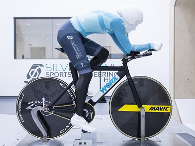 An athlete on a bike wearing an aerodynamic skinsuit in a lab